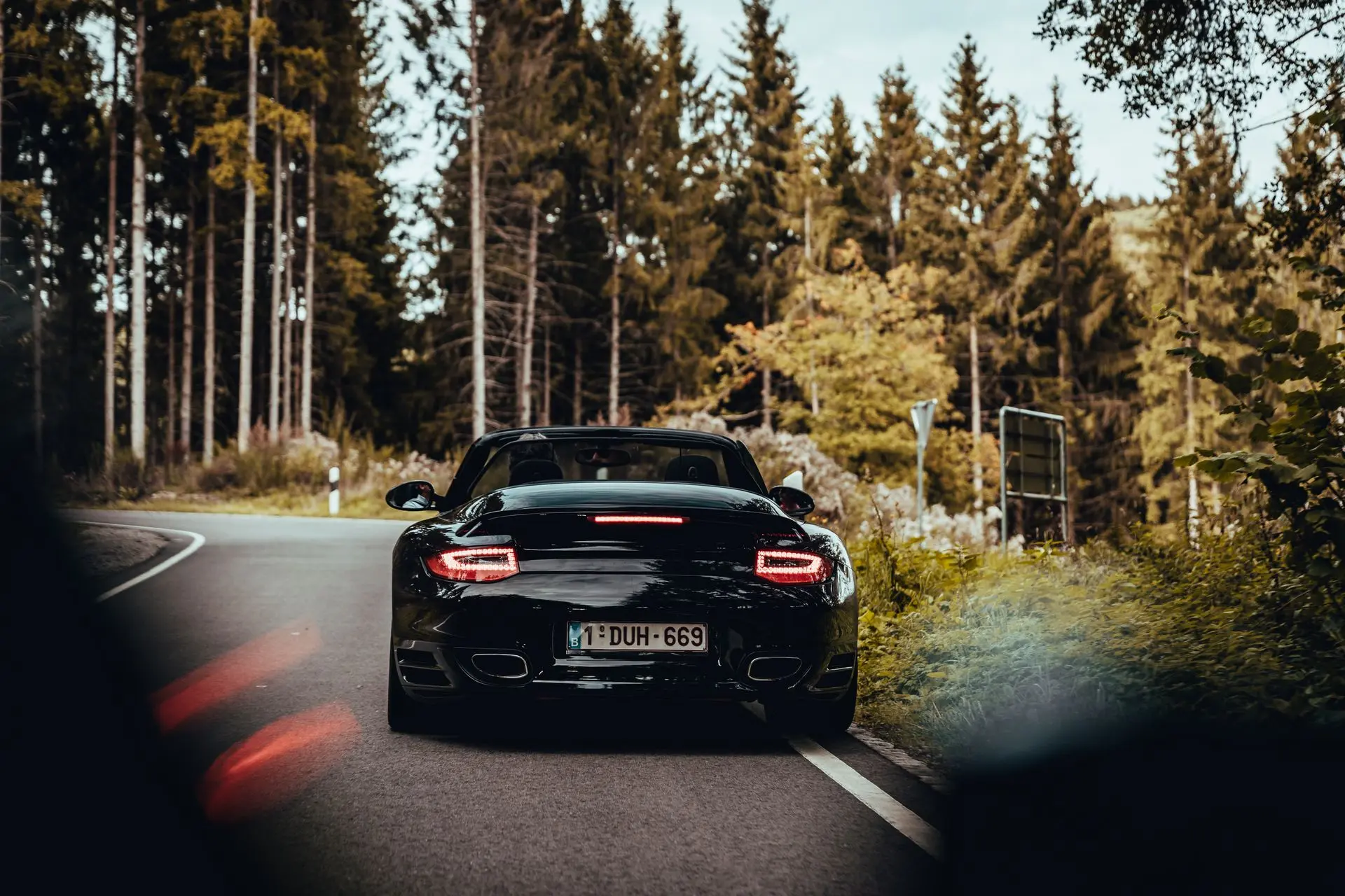 Black Porsche 911 convertible driving through the woods 1DUH669