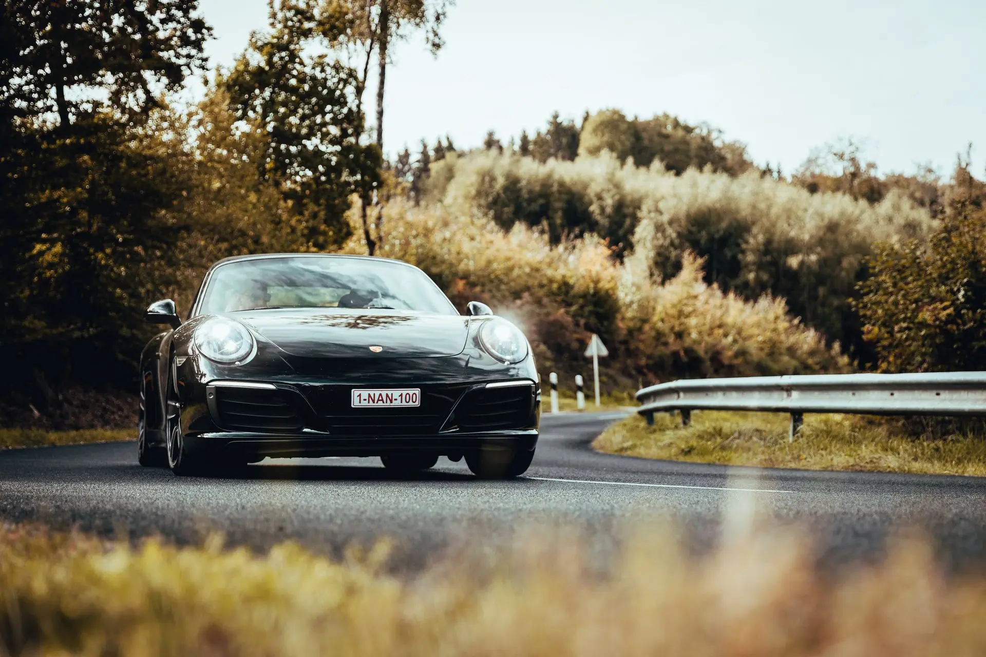 Black Porsche 911 1NAN100 driving curvy road