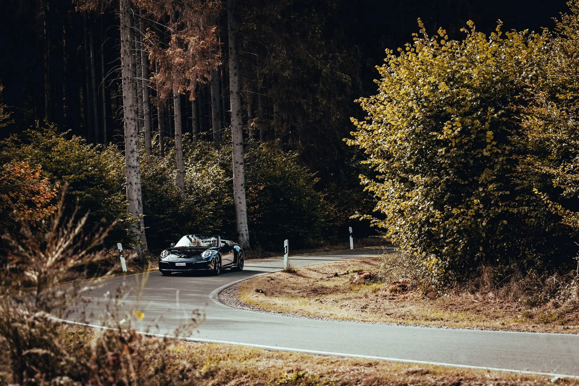 Black Porsche 911 convertible in the woods