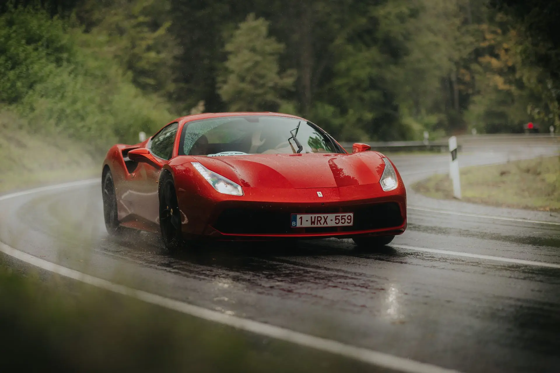 Red ferrari 458 driving in the rain