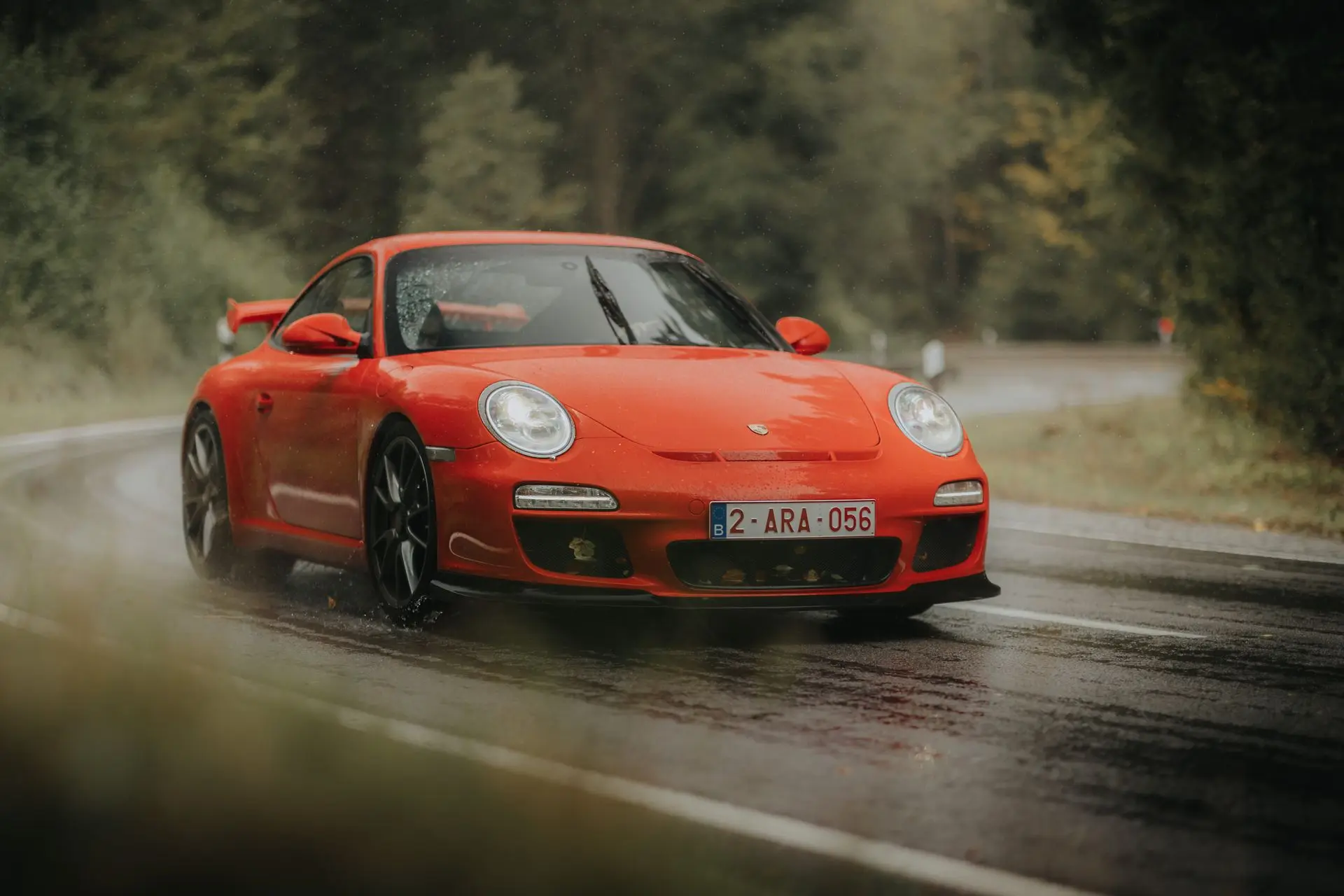Red Porsche 911 driving in the rain