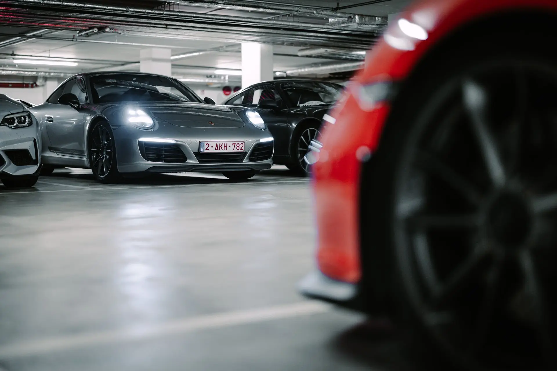 Red Porsche 911 and Gray Porsche 911 parked underground