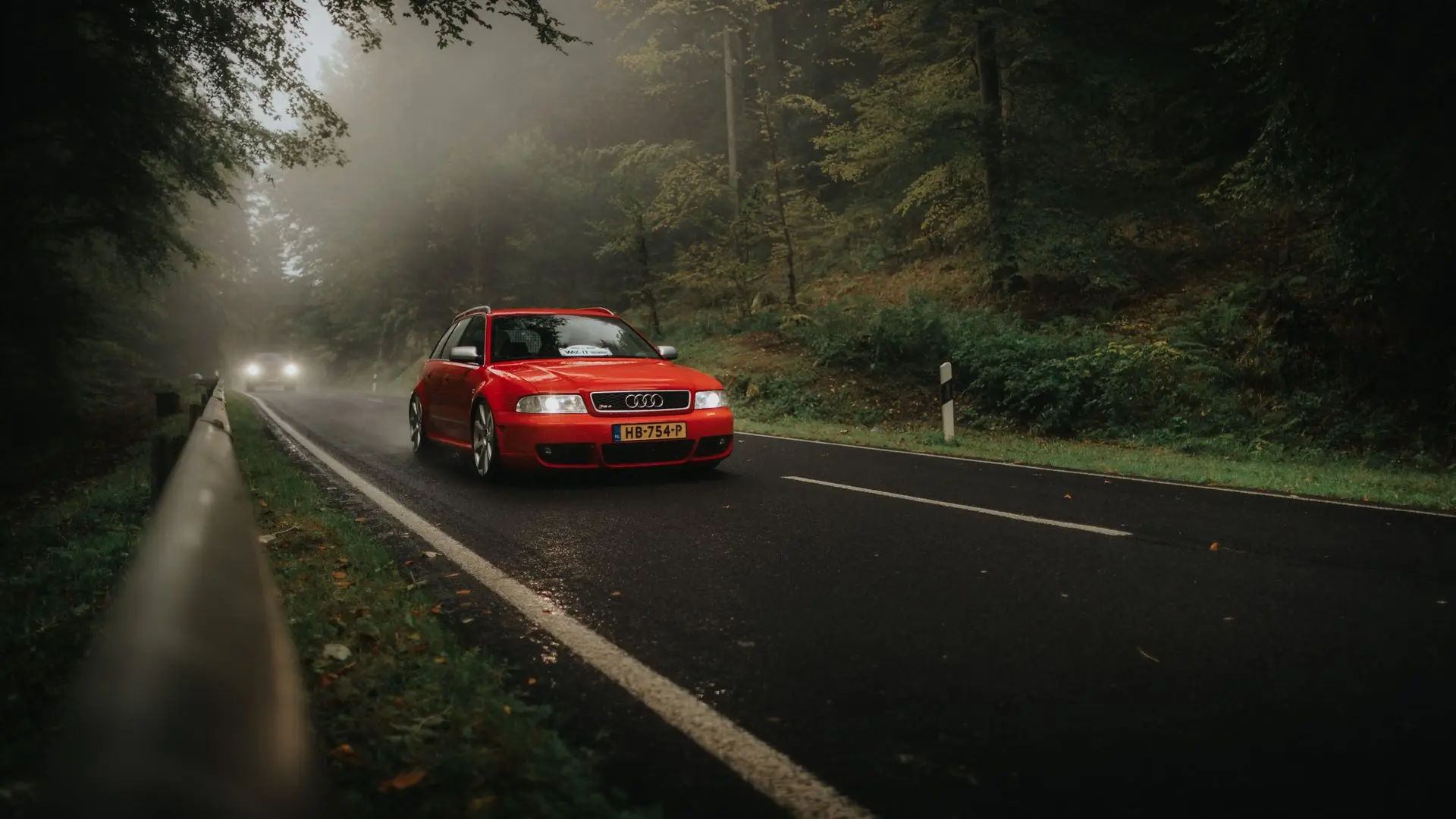 Red Audi RS4 classic car dutch plate driving trough a foggy wood