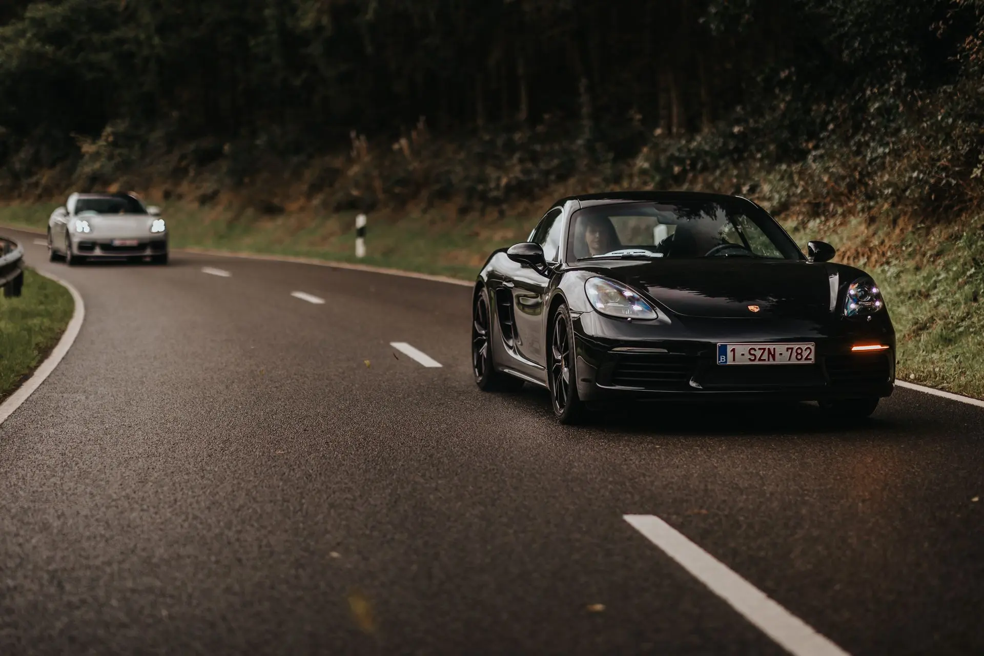 Black Porsche cayman on wet road