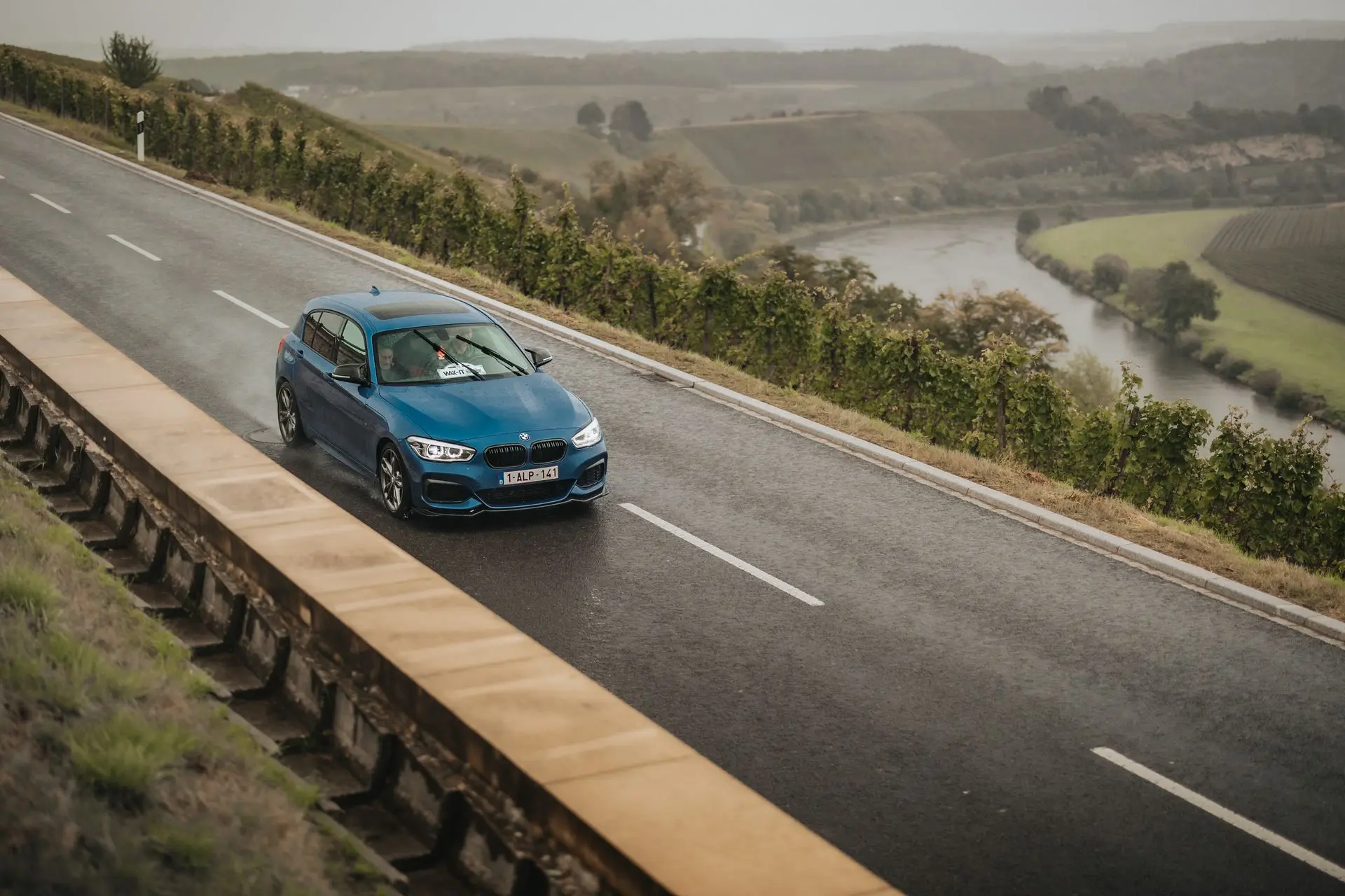 Blue BMW M140i on wet road