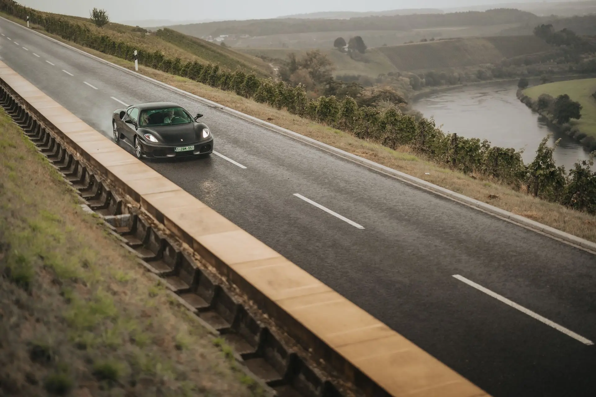 Ferrari sports car driving trough rain on a countryside road