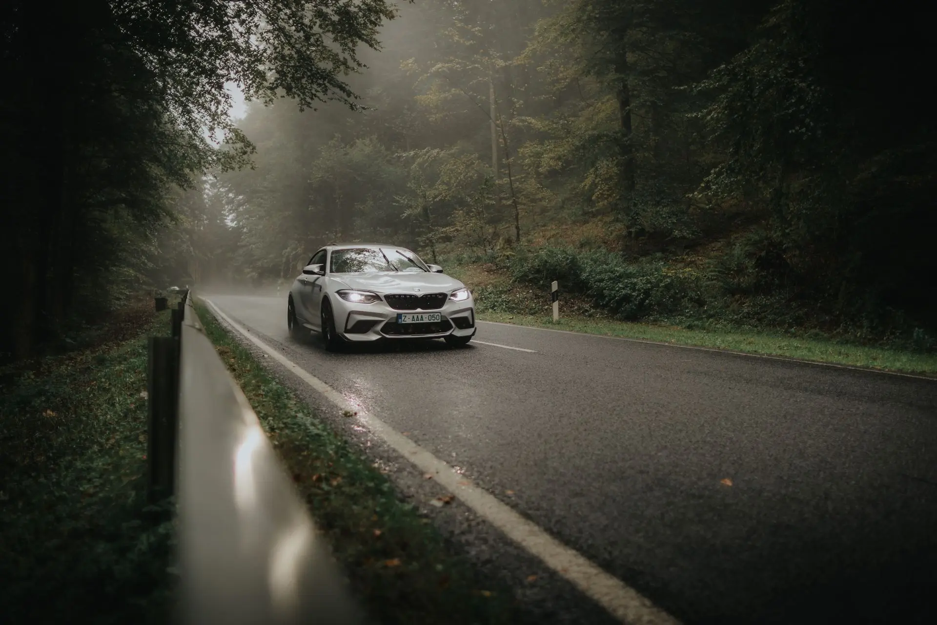 White bmw m2 on wet road in foggy forest