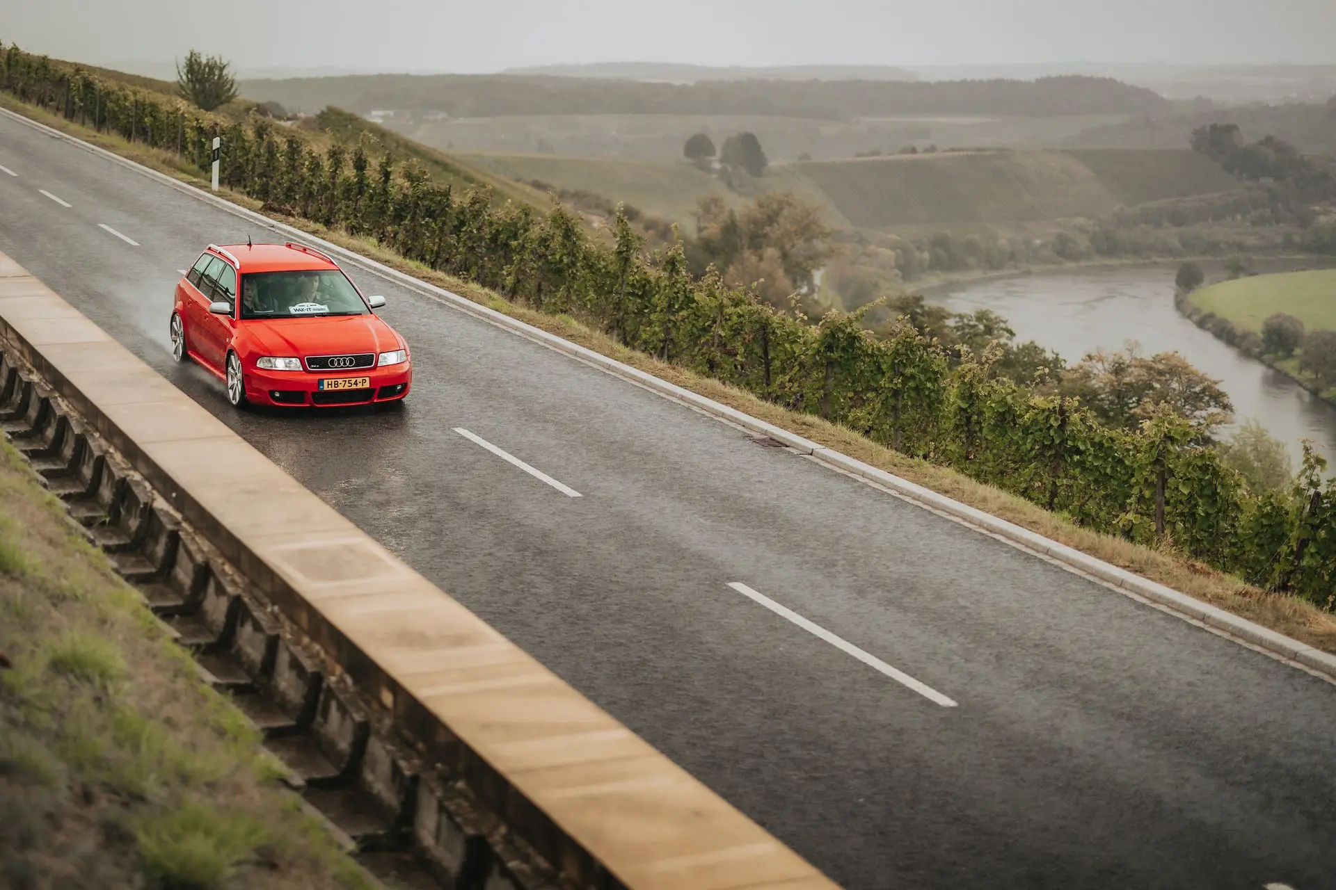 Red classic Audi RS4 driving trough the rain on a country road