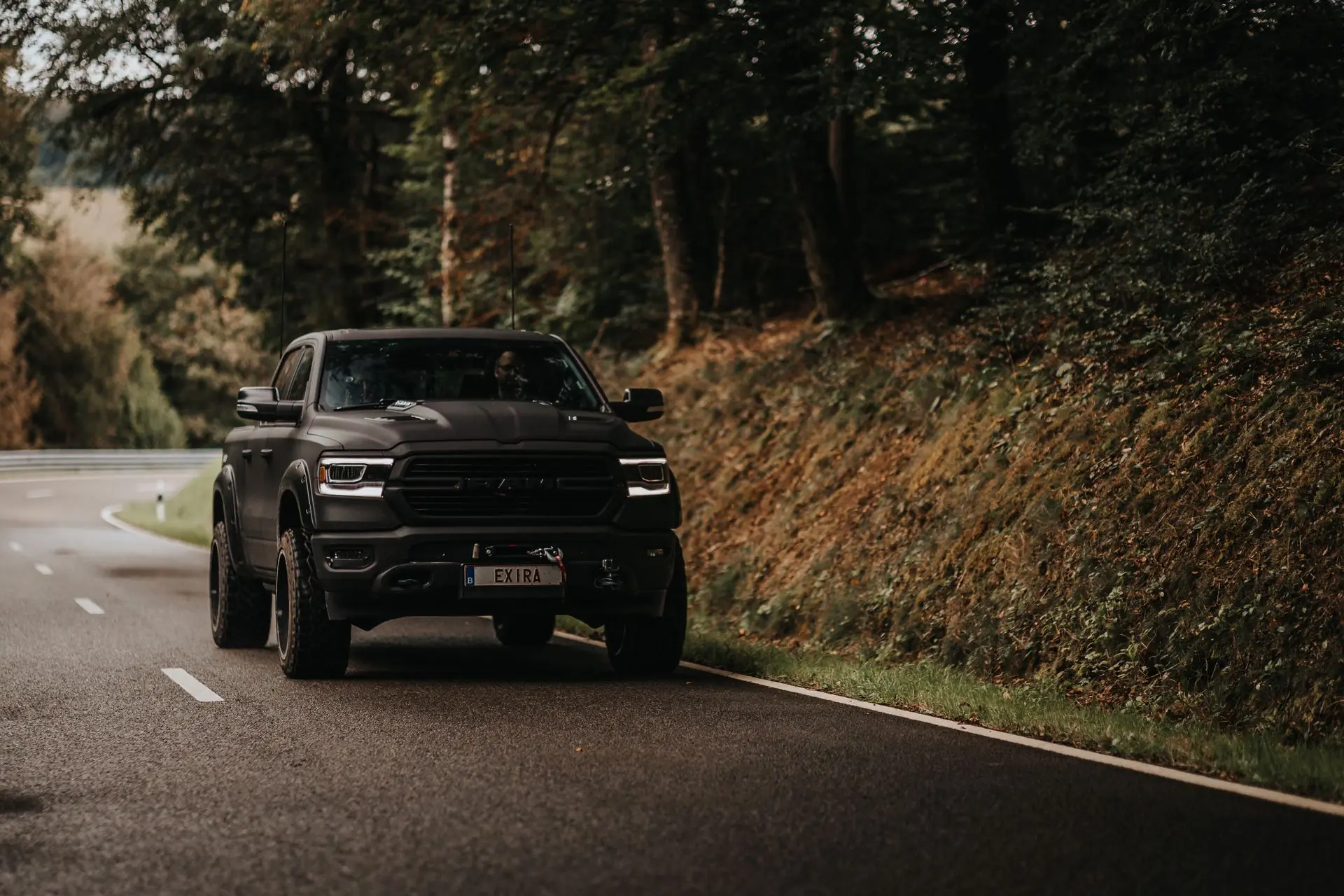 Exira matte black Dodge Ram driving on wet road