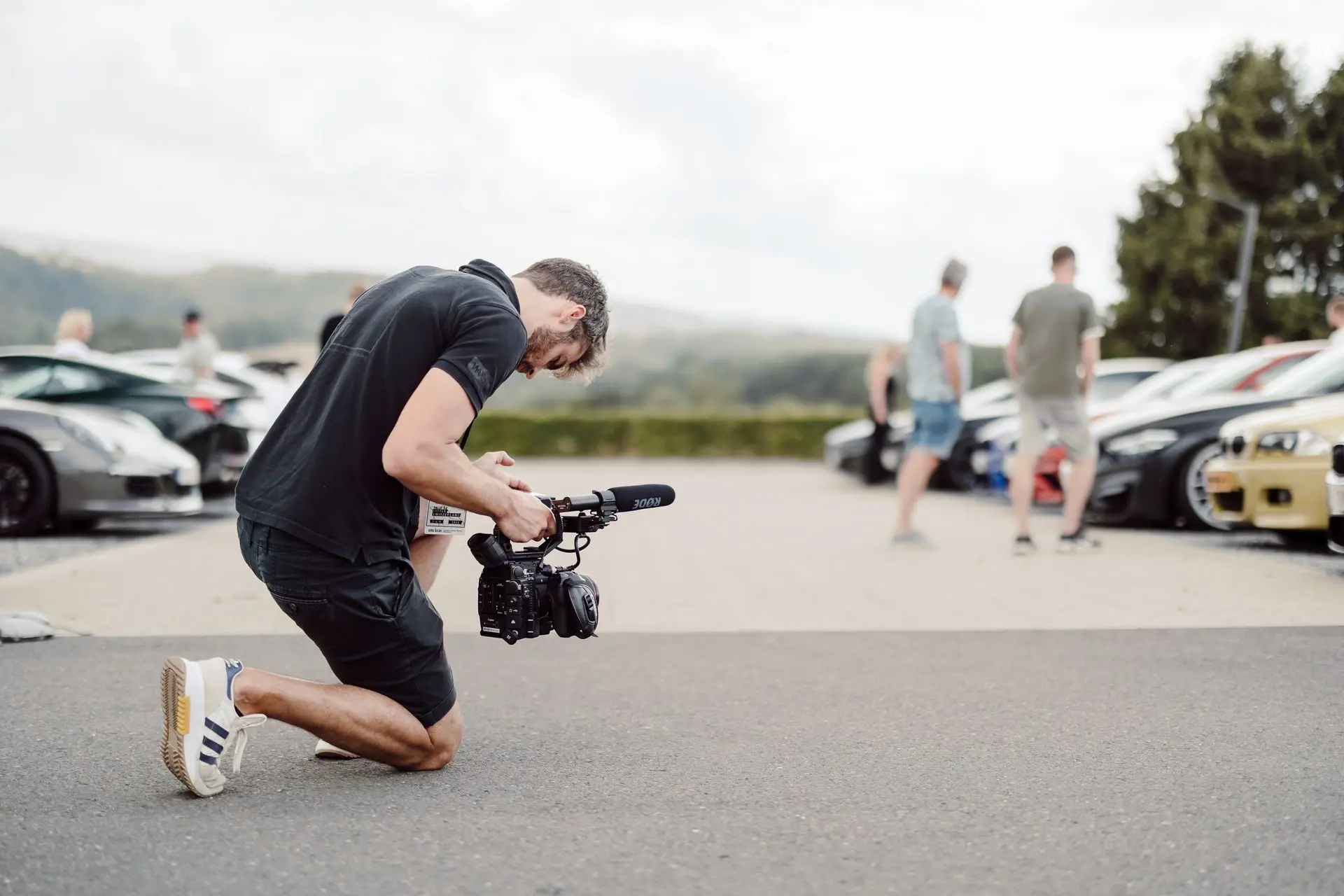 Male videographer recording cars in parking spot