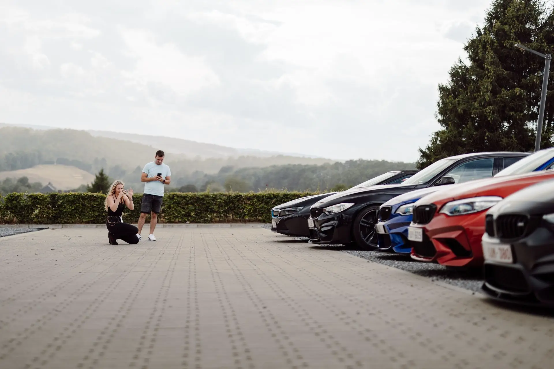 Woman and man photographing bmw